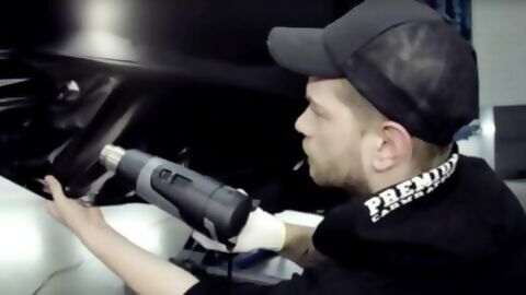 Ein Carwrapper foliert ein Auto mithilfe eines Heißluftgebläses