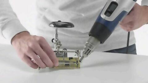 Ein Elektrobauteil auf einer Platine wird mithilfe eines Heißluftgerätes entlötet