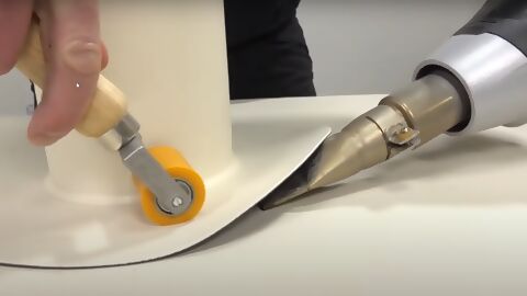 Mithilfe eines Heißluftgebläses und einer Andrückrolle wird eine Folie rund um eine Rohrdurchführung verschweißt