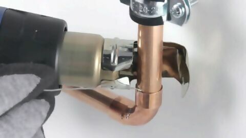Ein Verbindungsstück am Kupferrohr wird mithilfe eines Heißluftgerätes angelötet