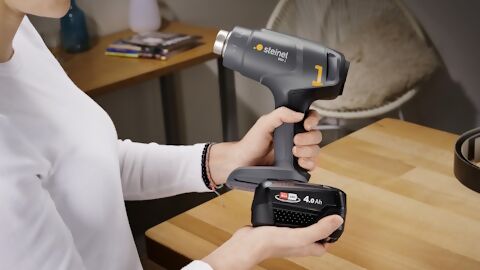Frau steckt ein Akku an das MobileHeat 1 von Steinel